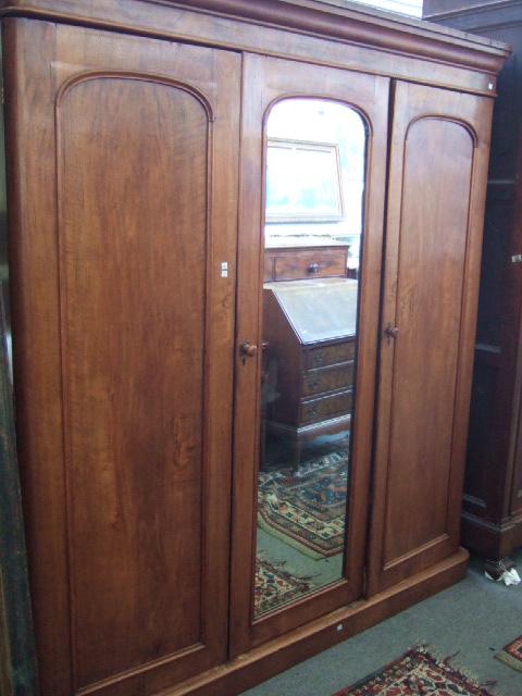 Appraisal: A Victorian walnut triple section wardrobe the mirrored central door