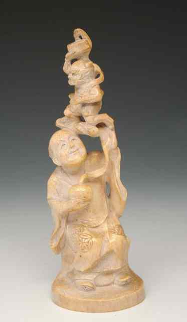 Appraisal: A JAPANESE CARVED IVORY FIGURE holding a smaller creature above