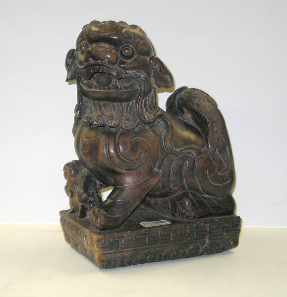 Appraisal: A pair of carved hardwood guardian lions Each with incised