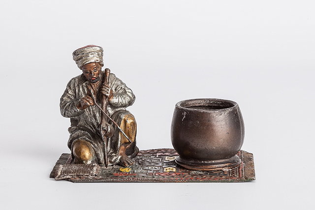 Appraisal: A METAL MODEL of a snake charmer seated on an