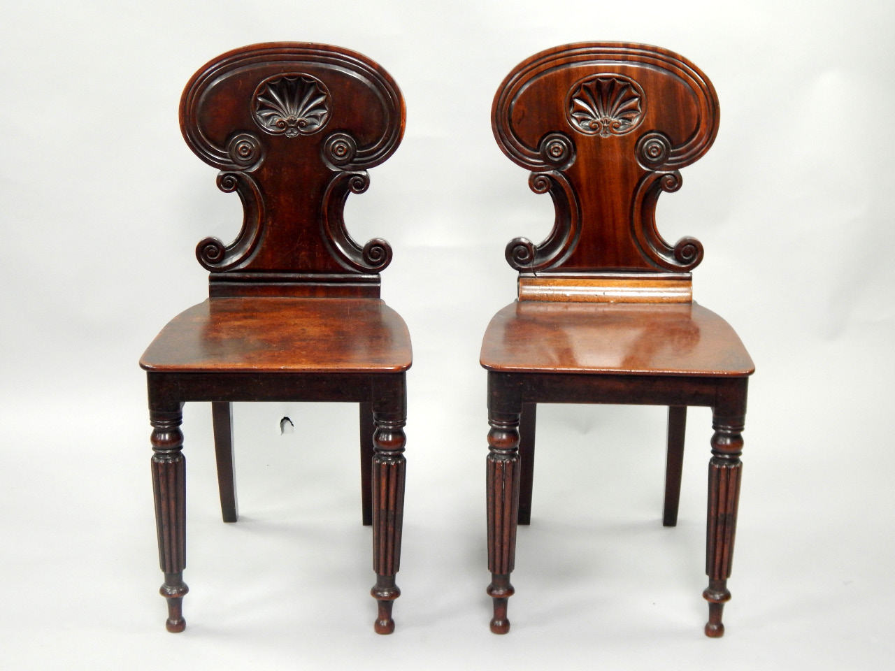 Appraisal: A pair of late Georgian mahogany hall chairs with scroll