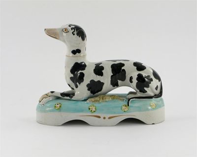 Appraisal: A Staffordshire model of a greyhound recumbent on a light