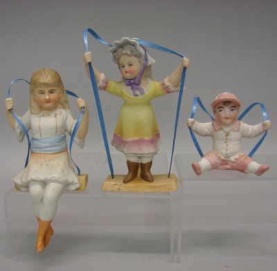 Appraisal: Lot of unmarked all bisque swing figurines Sitting boy and