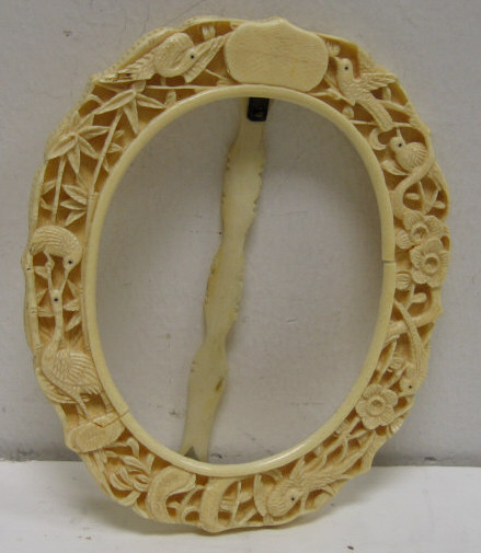 Appraisal: CARVED IVORY EASEL FRAME Shaped oval with high relief of