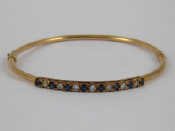 Appraisal: A yellow metal tests carat gold sapphire and diamond bangle