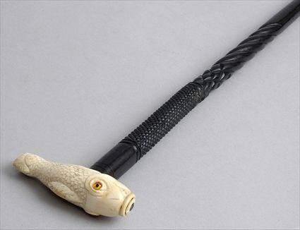 Appraisal: IVORY-HANDLED CARVED EBONY CANE The scaly open-mouth handle with glass