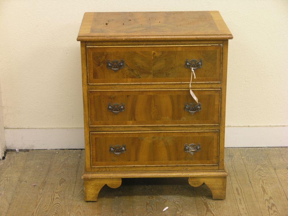 Appraisal: A reproduction yew veneered bedside chest of three drawers ft