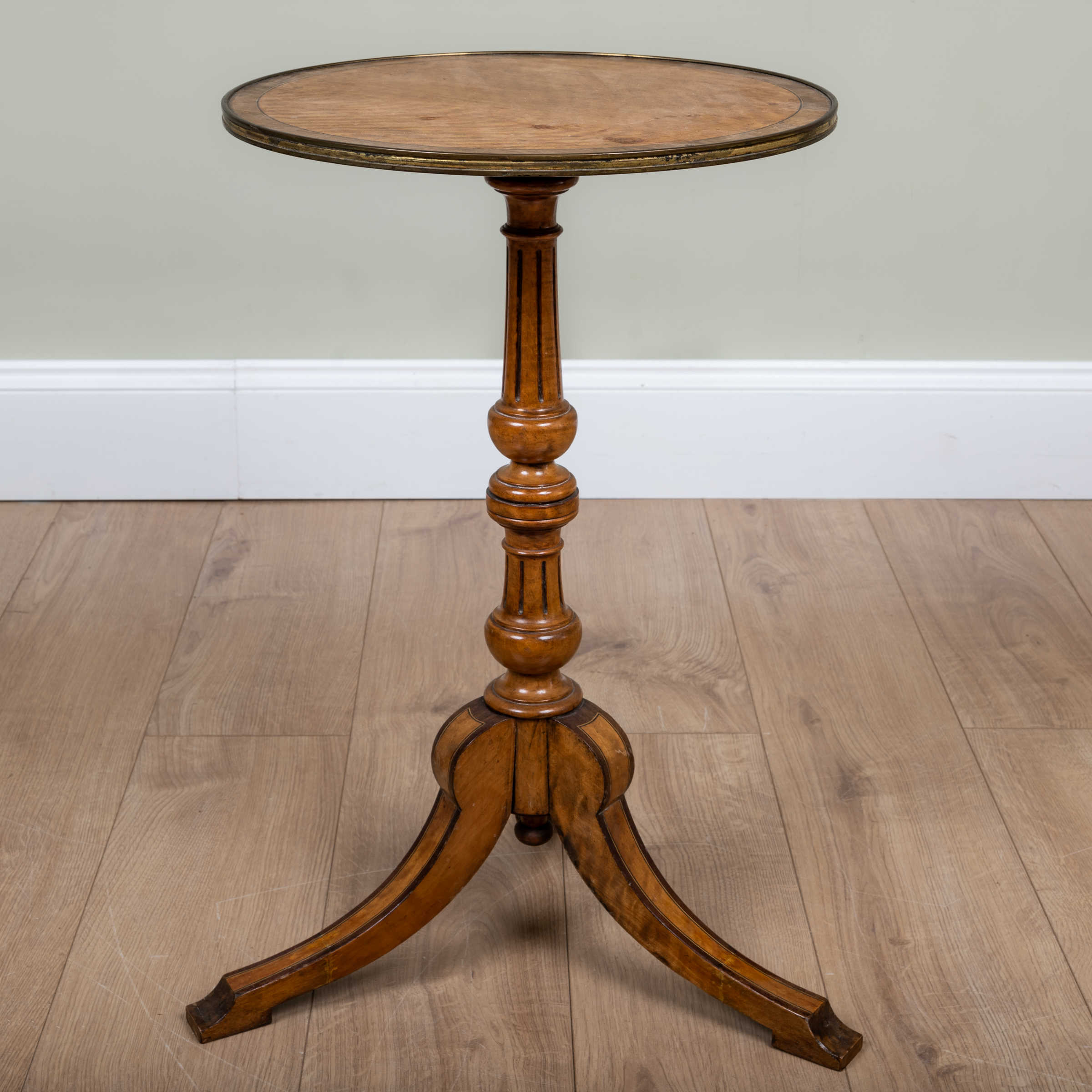 Appraisal: A satinwood circular tripod table with brass edging to the