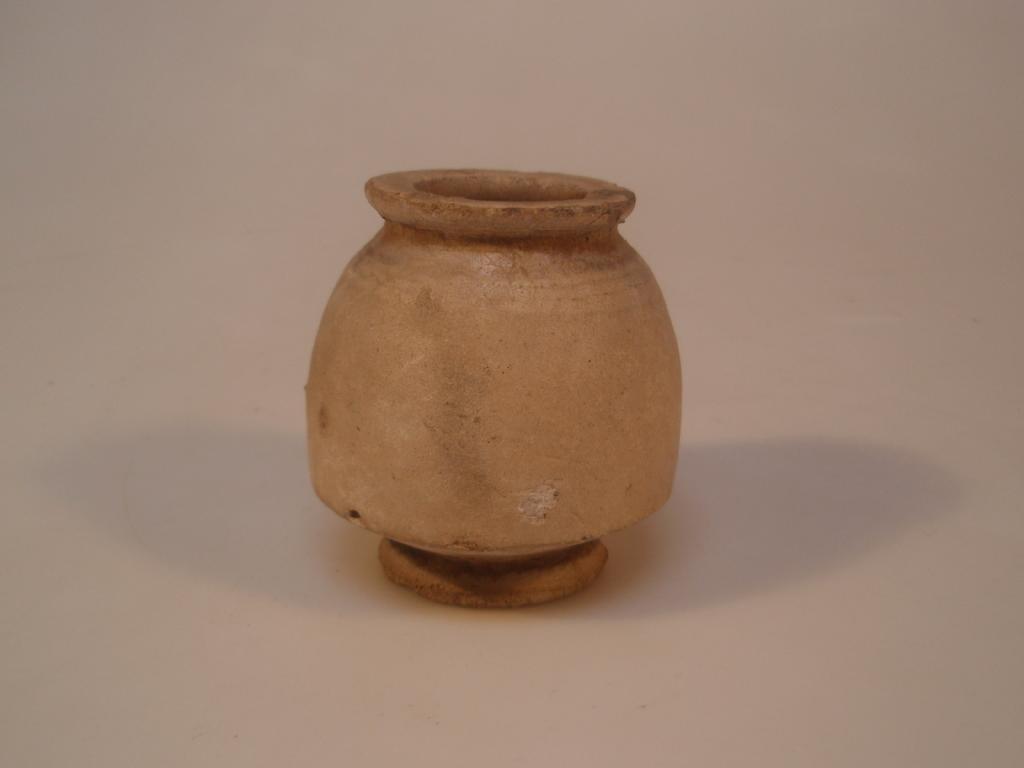 Appraisal: An ancient buff-coloured glazed pot with a flat mouth on