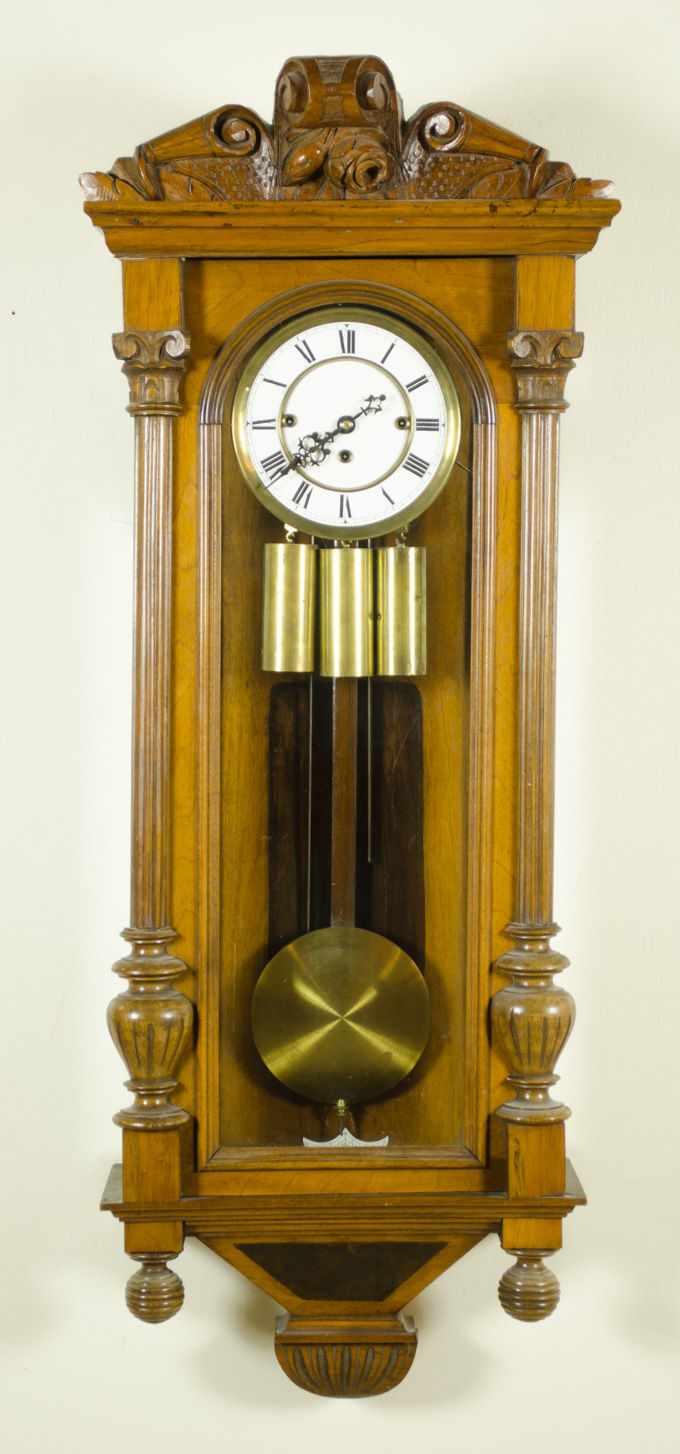 Appraisal: A CARVED WALNUT LONG-CASE WALL CLOCK Gustav Becker Clock Co