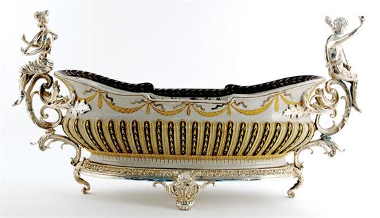 Appraisal: Porcelain and silver-mounted jardinere boat form mounted with putti on