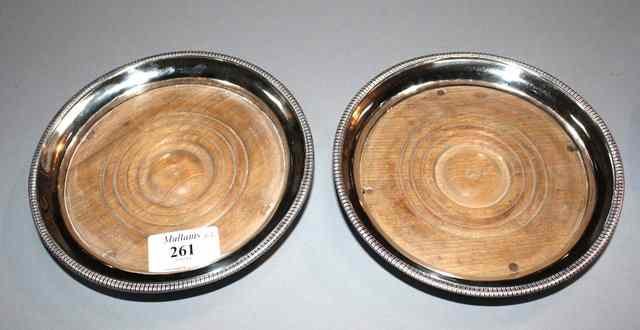 Appraisal: A PAIR OF GEORGE III SILVER BOTTLE COASTERS with flared