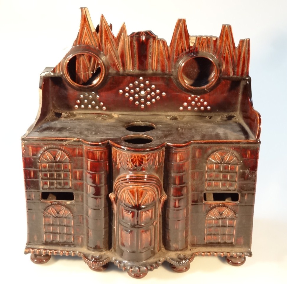 Appraisal: A thC treacle glazed pottery watch stand model of a