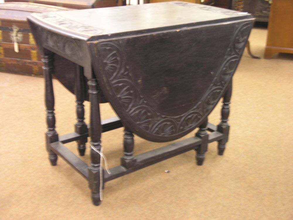 Appraisal: A dark stained solid oak gateleg table the top carved