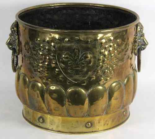 Appraisal: A circular embossed brass bucket with lion mask ring handles