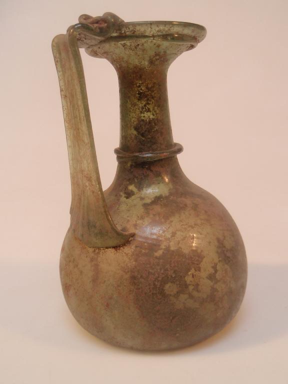 Appraisal: A late Roman greenish glass jug the funnel mouth decorated