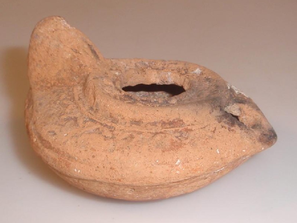 Appraisal: A moulded terracotta oil lamp some blackening around flame hole