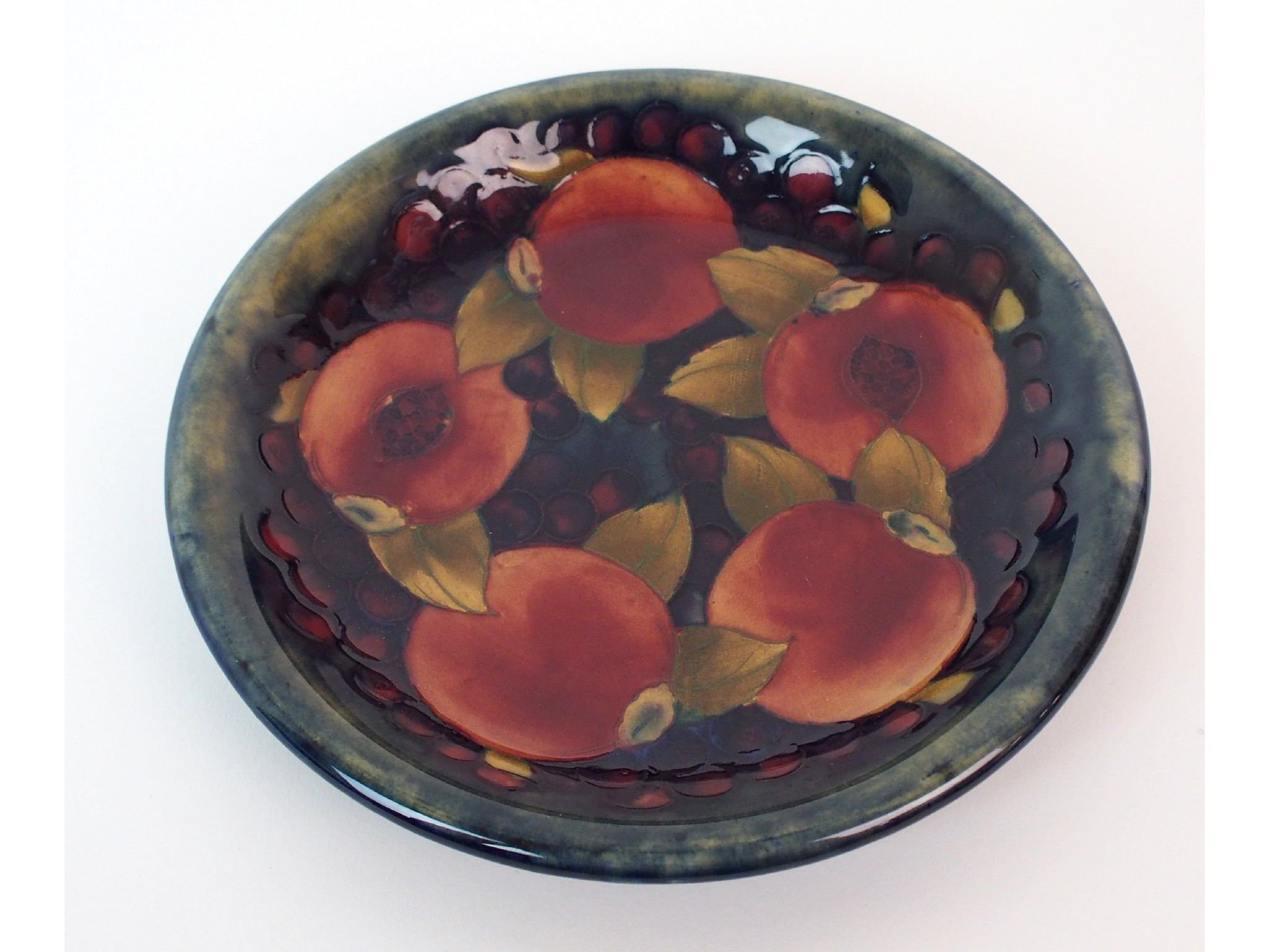 Appraisal: A Moorcroft Pottery Pomegranate dishpomegranates to centre on blue ground