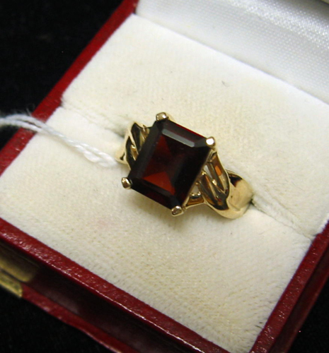 Appraisal: GARNET AND TEN KARAT GOLD SOLITAIRE RING centering an emerald-cut