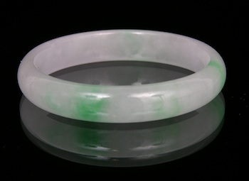 Appraisal: A Carved White and Green Jadeite Bangle Chinese A well-carved