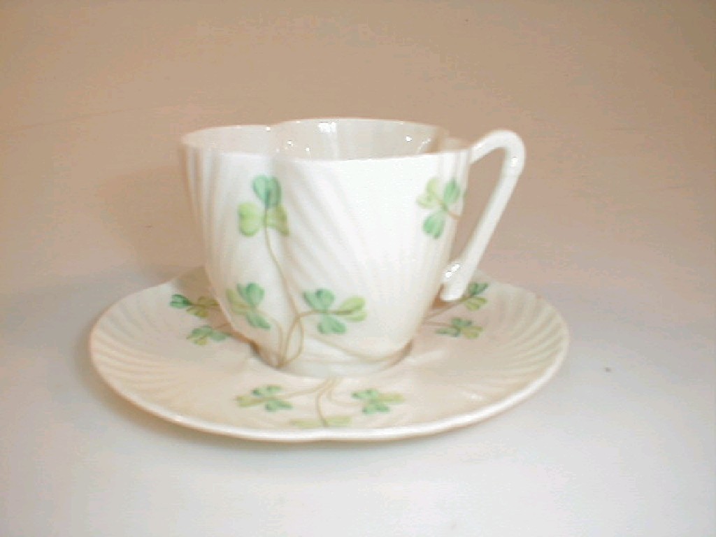 Appraisal: A Belleek shell shape cup and saucer painted with shamrocks