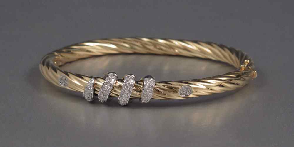 Appraisal: KT GOLD DIAMOND TWIST BANGLE BRACELET Yellow gold hinged bangle