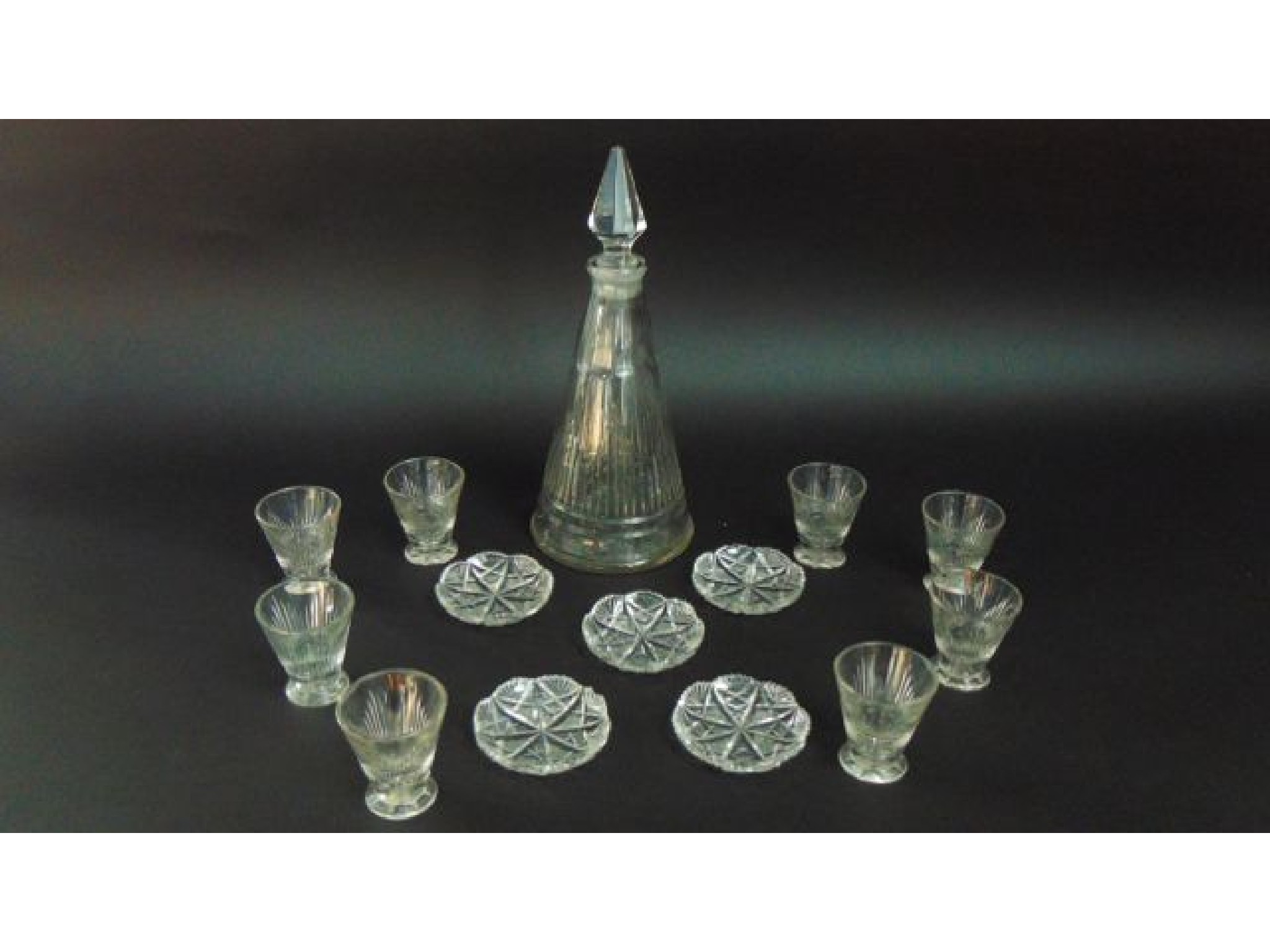 Appraisal: A heavy cut glass steeple shaped decanter conical shaped shot