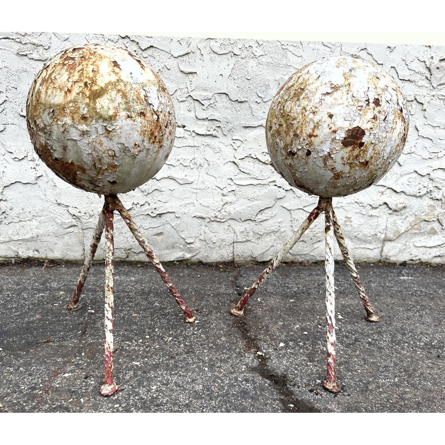 Appraisal: Pair of Cannonballs on Twisted Iron Tripod Bases Garden sculptures