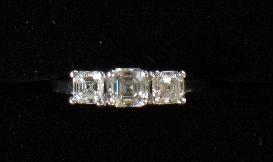 Appraisal: A THREE STONE DIAMOND RING the central square-cut diamond flanked