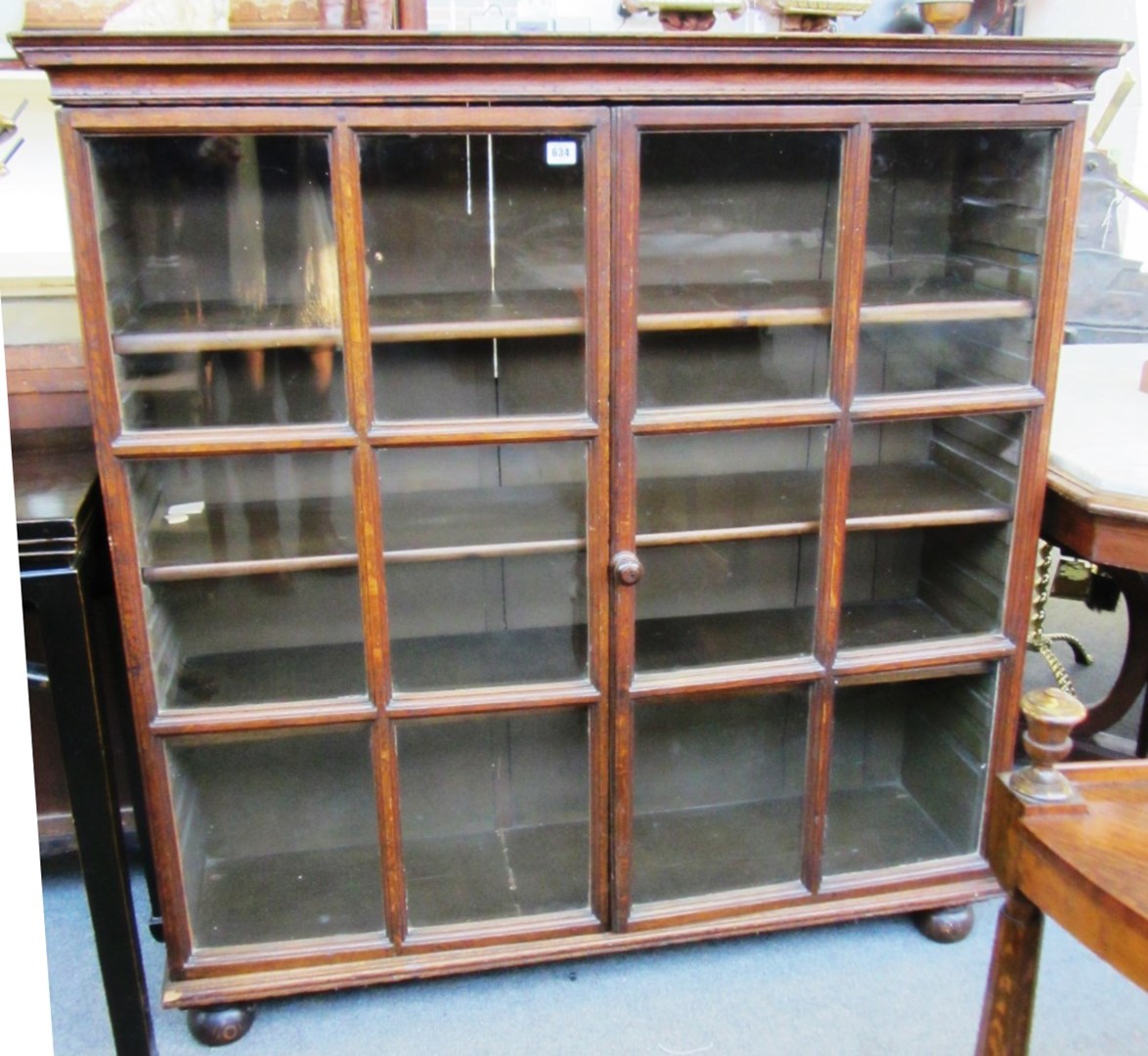 Appraisal: An th century oak glazed two door bookcase on bun