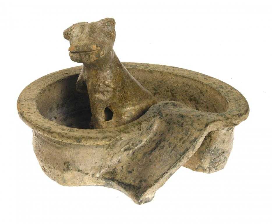 Appraisal: A GREEN GLAZED EARTHENWARE MODEL OF A DOG IN A