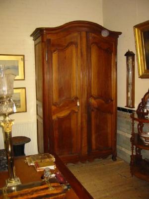 Appraisal: A FRENCH PROVINCIAL WALNUT ARMOIRE the arched moulded cornice over