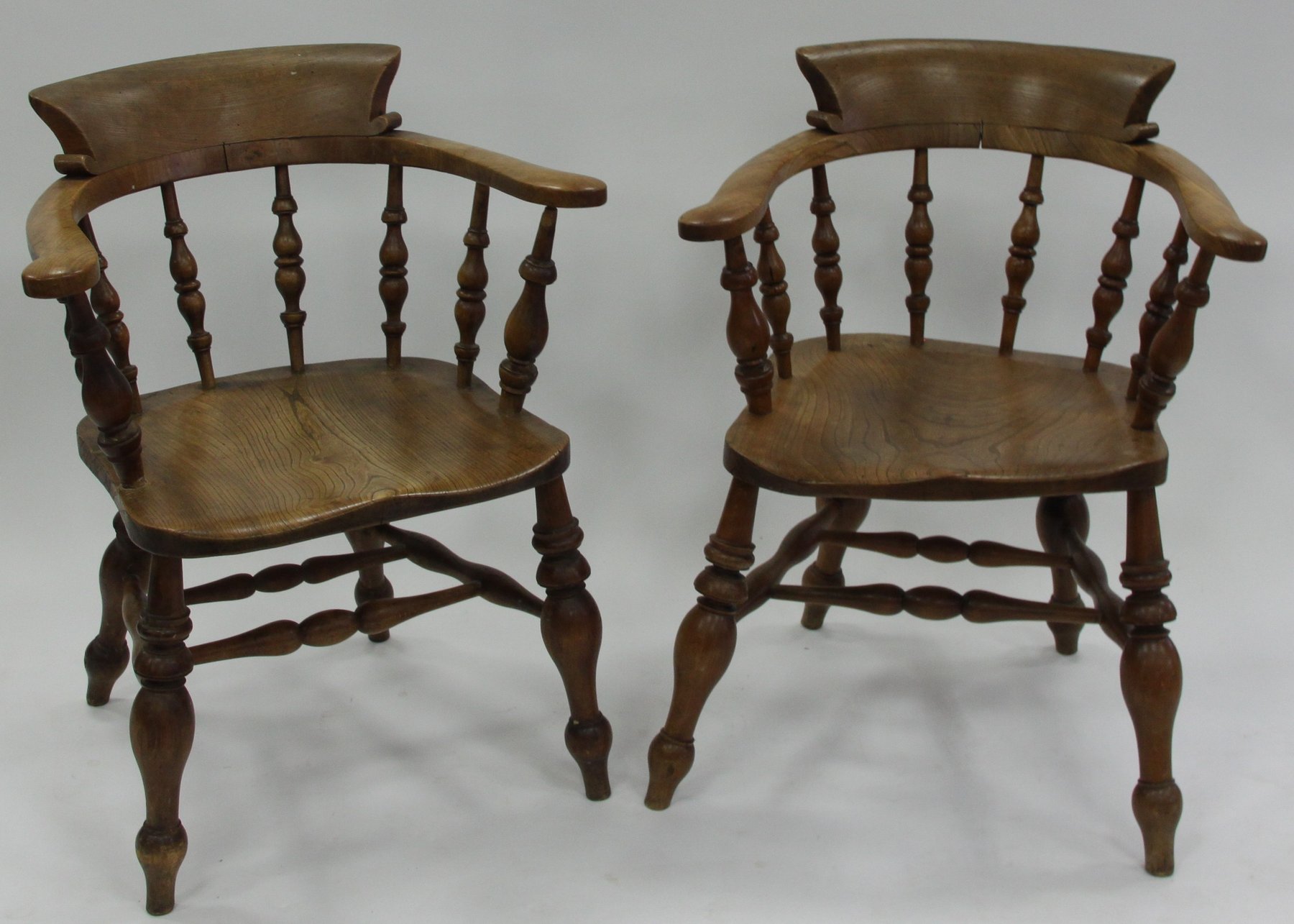 Appraisal: Two elbow chairs each with turned spindle back dished seat