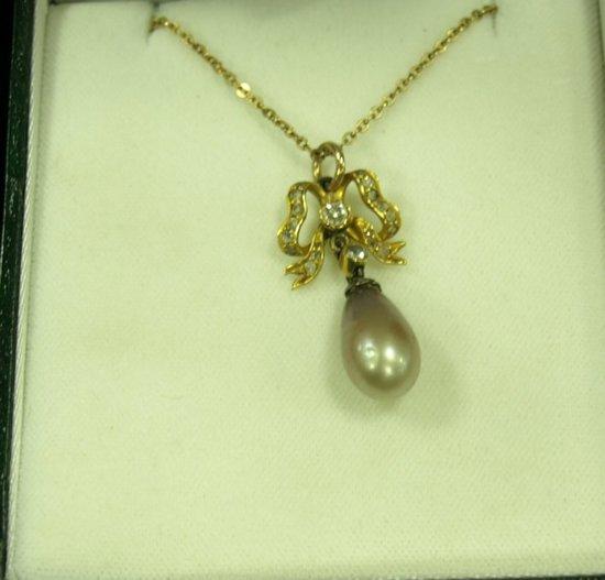 Appraisal: A ct gold bow shaped pendant set a central diamond