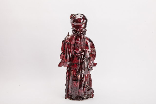 Appraisal: A CHINESE AMBER COLOURED NATURAL RESIN CARVING of a sage