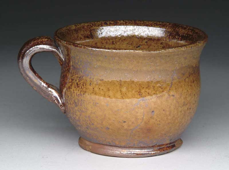 Appraisal: GLAZED REDWARE HANDLED CUP Footed cup has an orange to