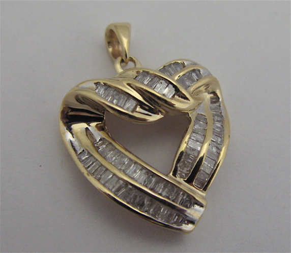 Appraisal: DIAMOND AND KARAT GOLD HEART PENDANT covered with tapered baguette