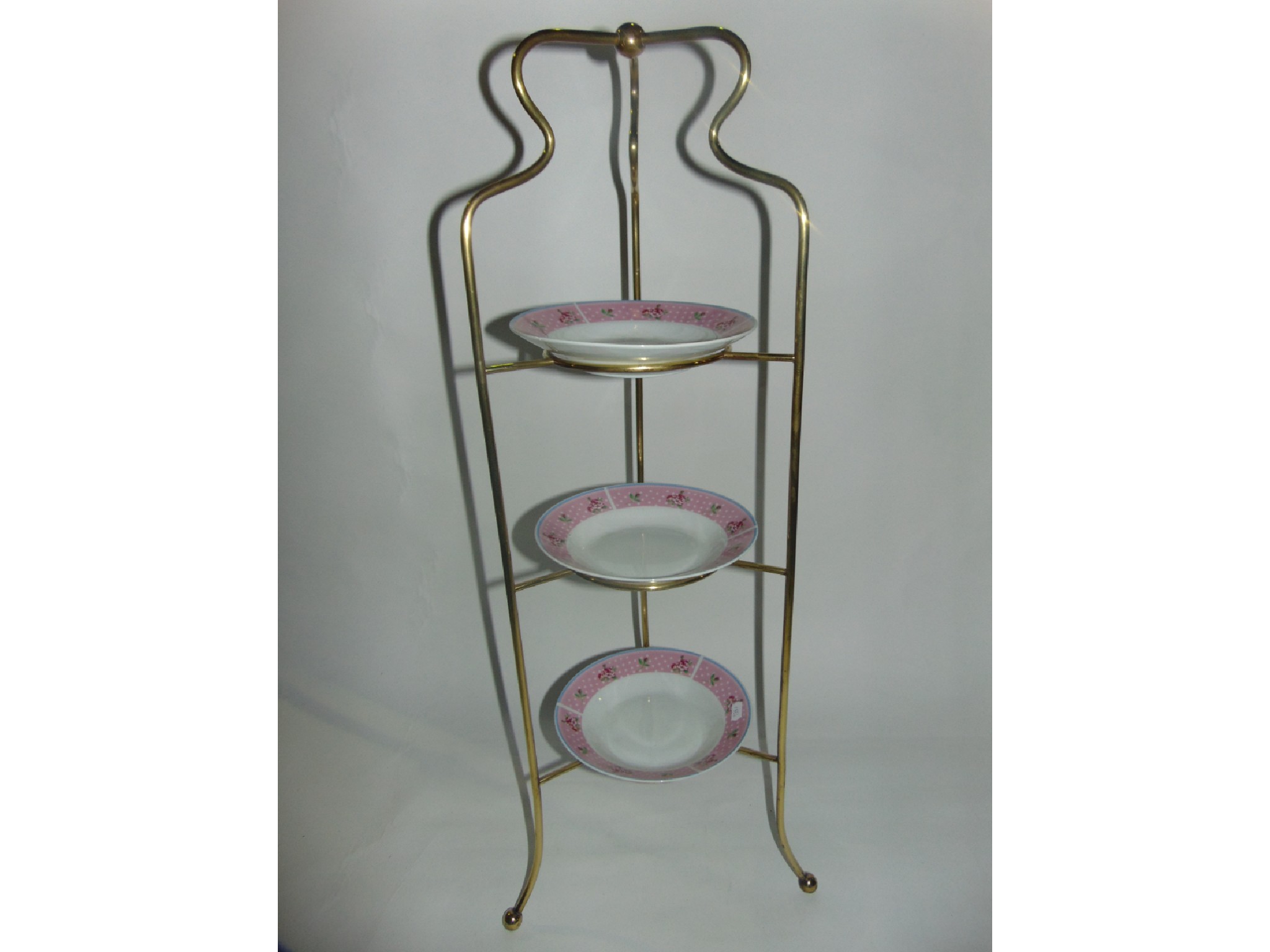 Appraisal: A brass three tier plate stand raised on ball supports