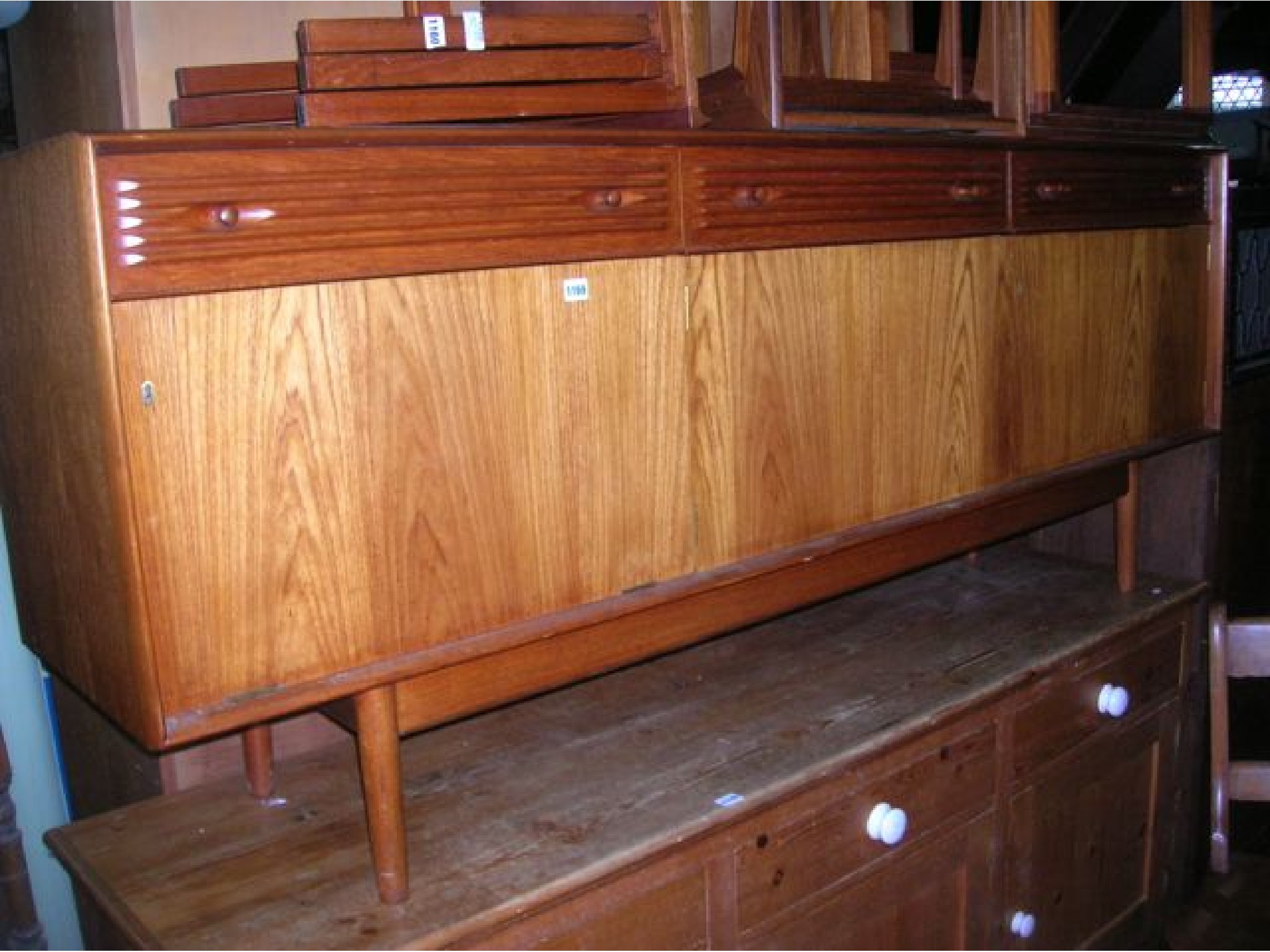 Appraisal: A mid th century long teak sideboard enclosed by three