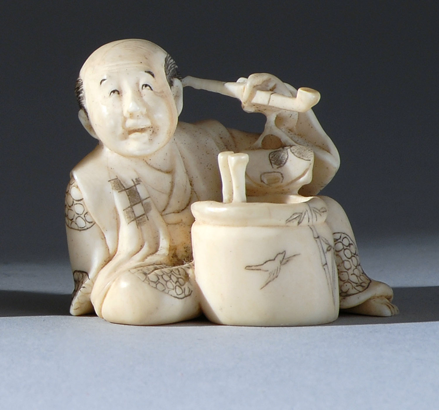 Appraisal: IVORY NETSUKE Circa Depicting a seated man beside an hibachi