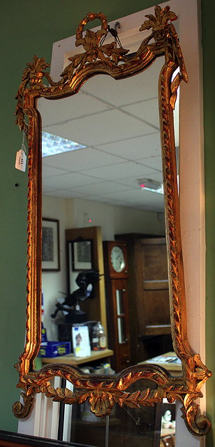 Appraisal: A CARVED GILT WOOD HANGING WALL MIRROR with shaped mirror