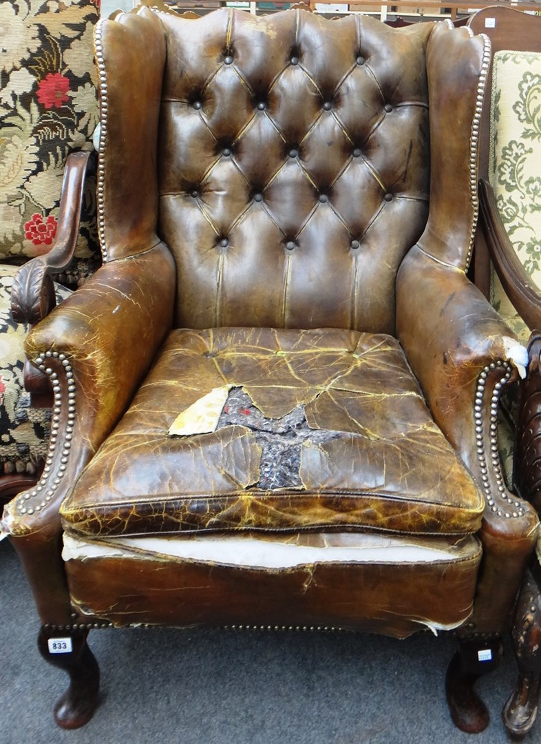 Appraisal: An th century style brass studded leather wingback armchair on