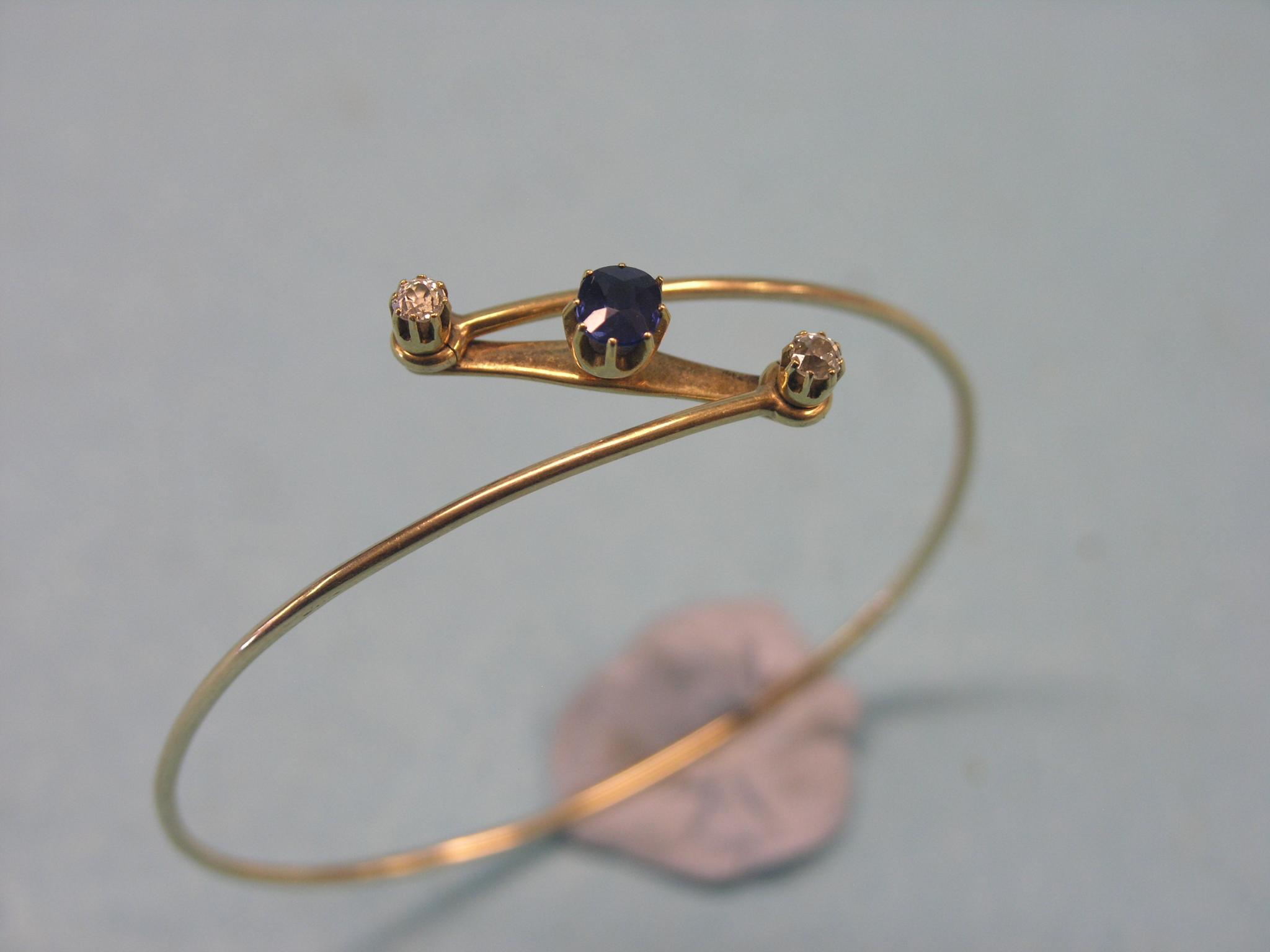 Appraisal: A Victorian yellow metal bangle claw-set single sapphire and two