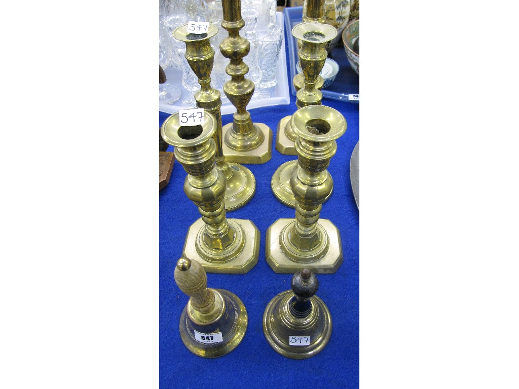 Appraisal: Lot comprising three pairs of brass candlesticks and two handbells