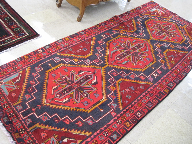 Appraisal: PERSIAN TRIBAL CARPET featuring three red hexagonal medallions on dark