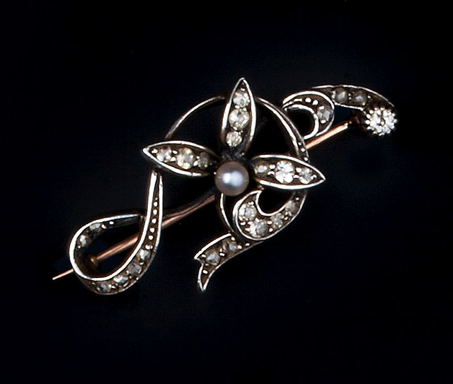 Appraisal: A DIAMOND AND HALF PEARL BROOCH of scrolled foliate design