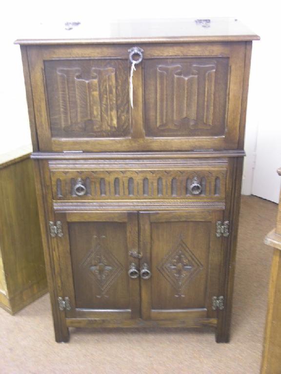 Appraisal: A dark oak cocktail cabinet linenfold cupboard doors enclosing illuminating