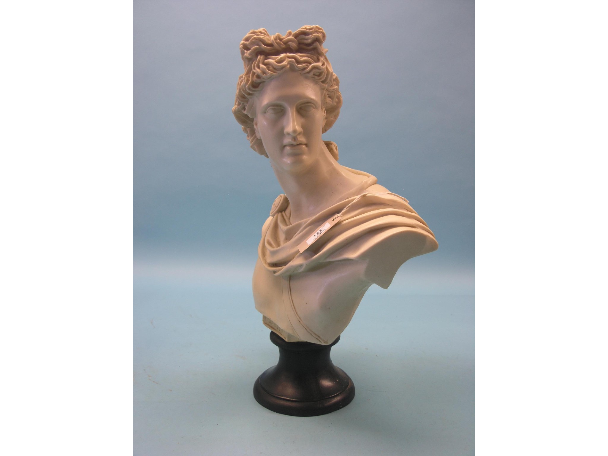 Appraisal: A moulded resin portrait bust Apollo marble-effect on ebonised socle