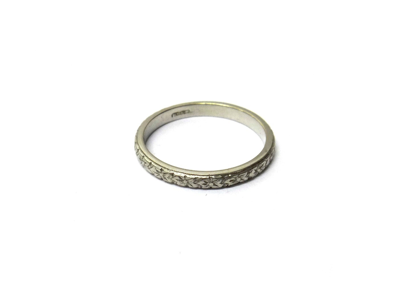 Appraisal: A platinum wedding ring with engraved floral decoration ring size