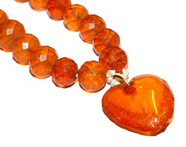 Appraisal: A FACETED CLEAR ORANGE AMBER BEAD NECKLACE with attached heart